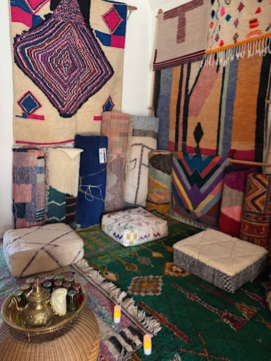 Poufs on the floor with tea set in the foreground and rugs hanging from the walls