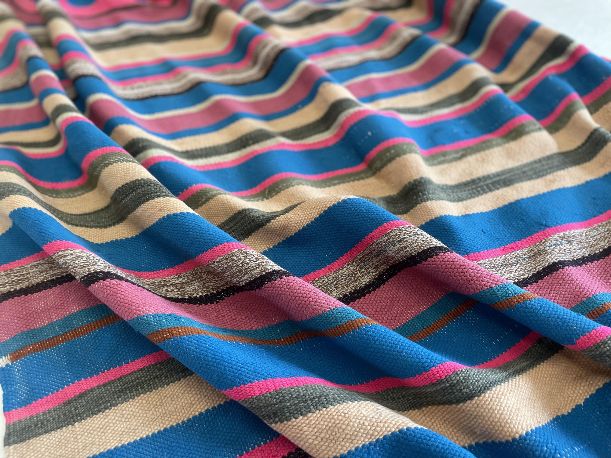 pink and blue striped Moroccan blanket on the ground