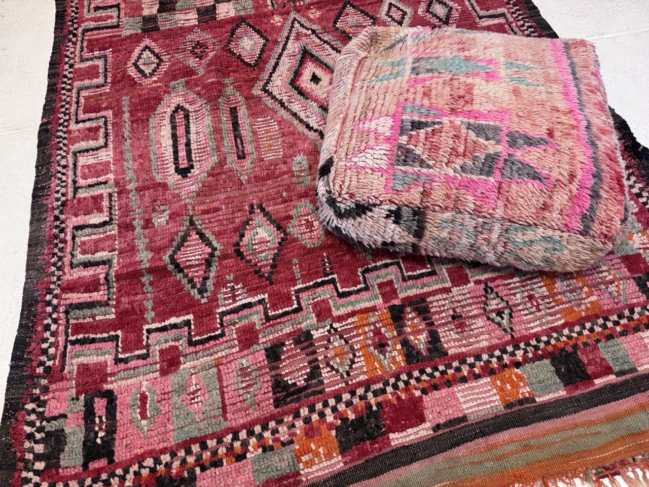 vintage moroccan rug in pinks and reds with fluffy pink floor pouf